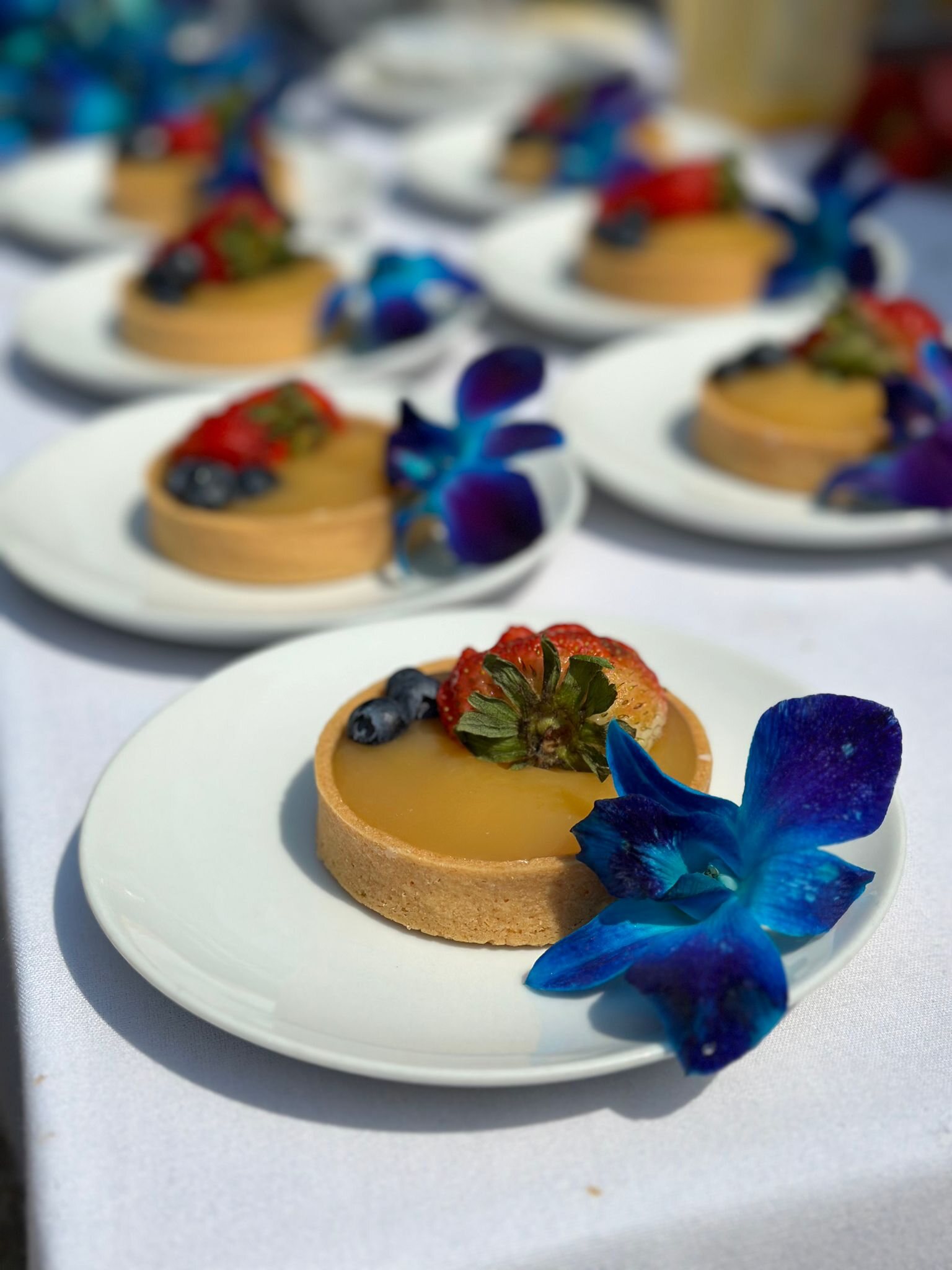 Lemon tarts with fresh strawberries, blueberries and blue orchids