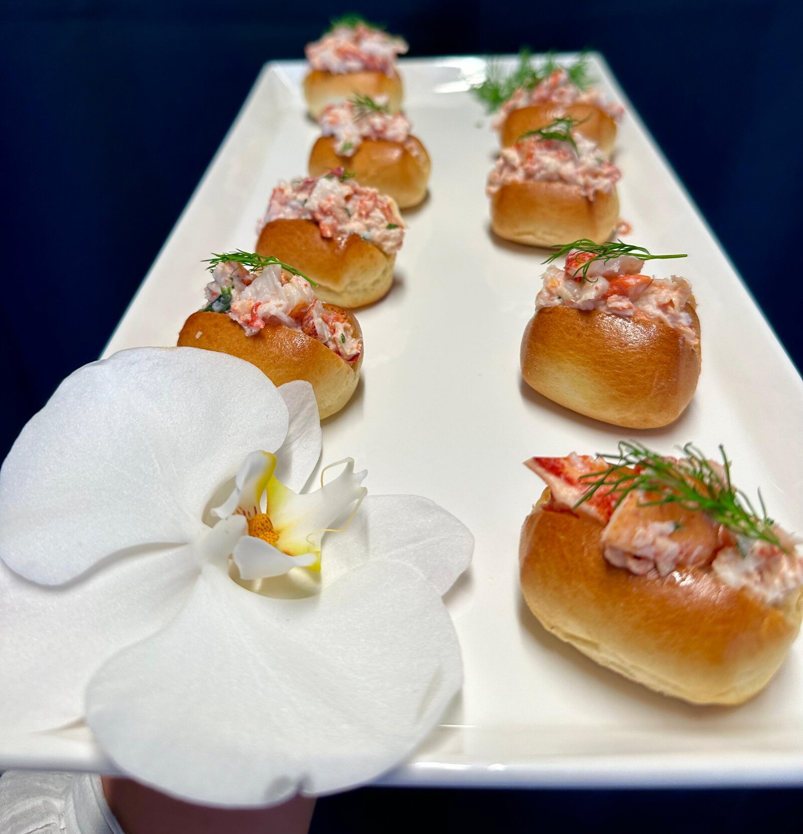 Mini lobster rolls garnished with a white orchid