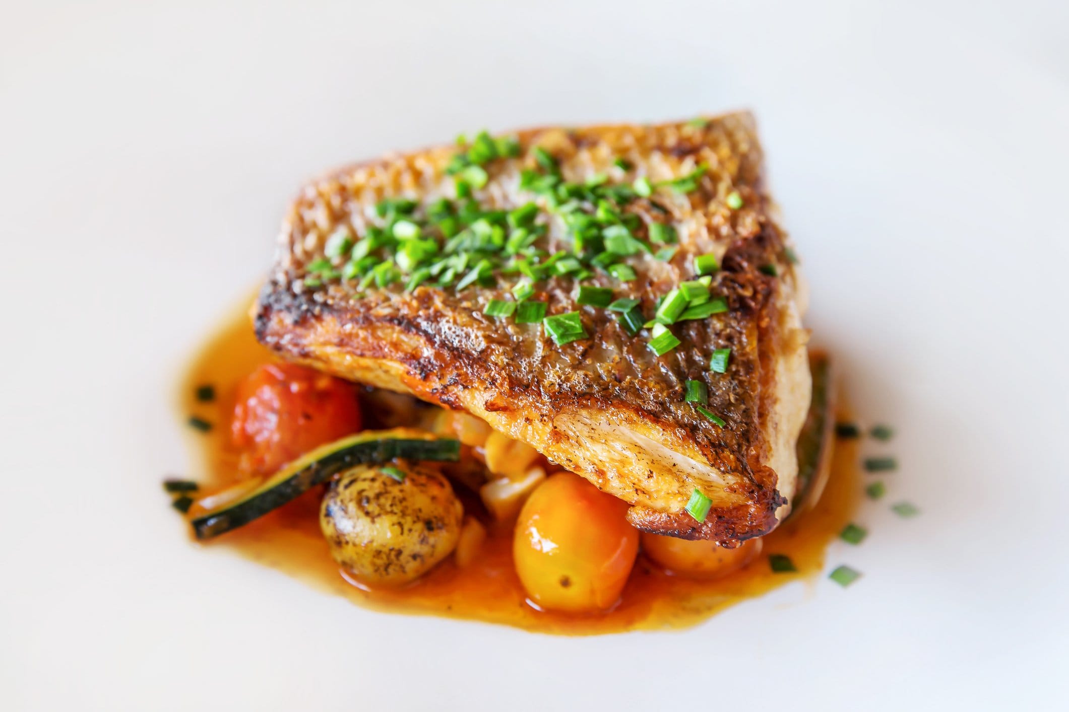 Plated crispy-skin fish fillet with seasonal vegetables