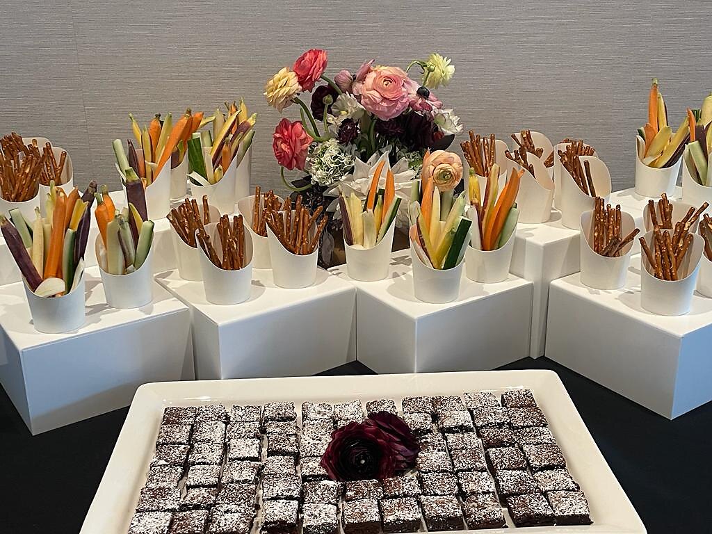 Crudite cups, pretzel sticks and brownie squares arranged for all-day snack service