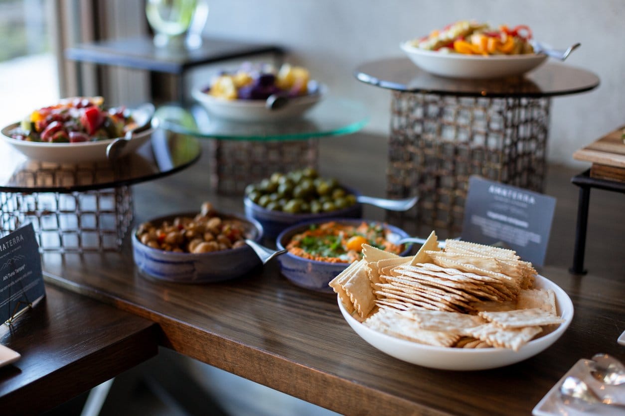 Grazing table with salads, olives, hummus and crackers on tiered stands