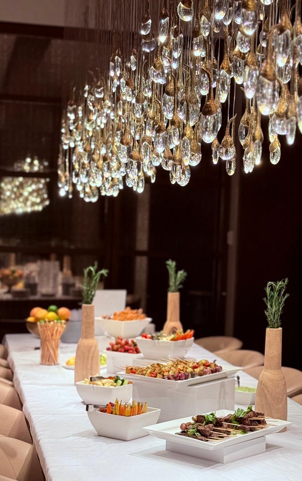 Buffet dinner beneath a crystal chandelier at an evening celebration