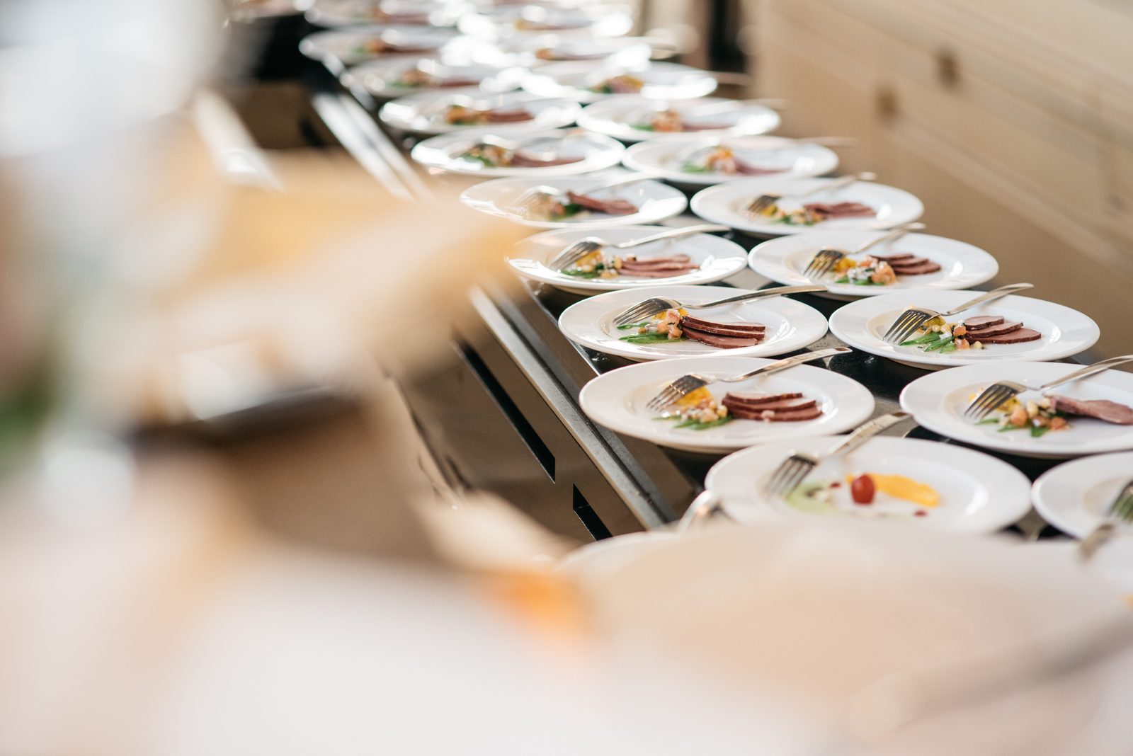 Rows of identical plated courses with forks staged for synchronized service