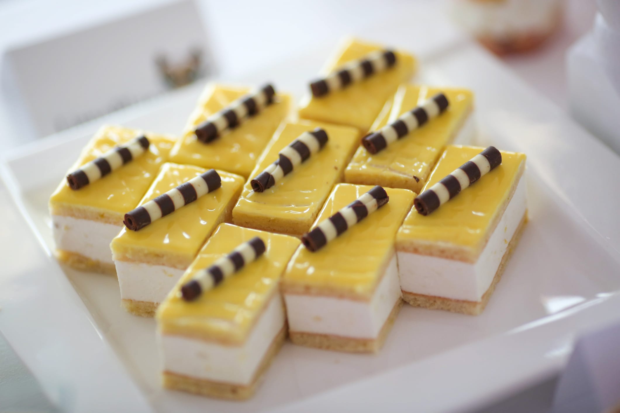 Mango and lemon mousse dessert squares topped with chocolate cigarillos